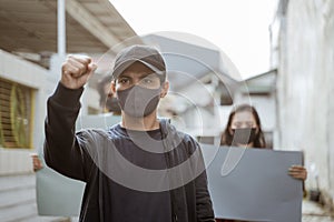 Portrait man students demonstrating with their friends holding blank paper in the background