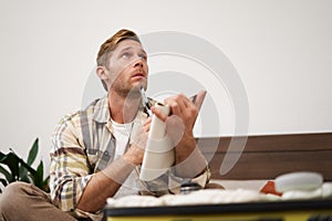 Portrait of man with suitcase, sitting and packing things for holiday, checking list of items for vacation, writing down