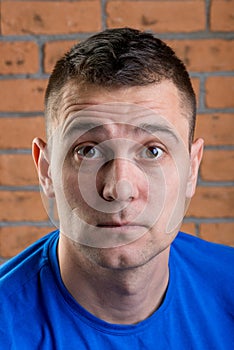 Portrait of a man with surprise on his face against a brick wall