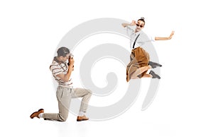 Portrait of man taking photo of beautiful stylish woman in a jump isolated on white background. Retro style