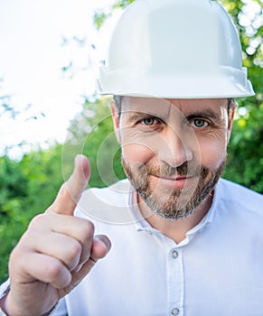 Portrait of man taskmaster in hardhat pointing finger outdoors photo