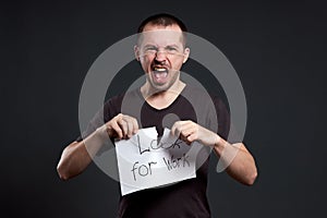 Portrait of a man tearing up an inscription on paper looking for a job