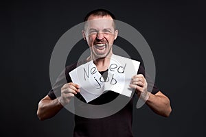 Portrait of a man tearing up an inscription on paper need a job