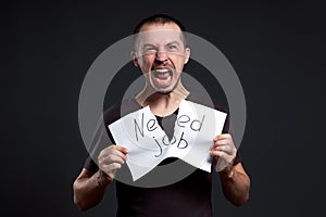 Portrait of a man tearing up an inscription on paper need a job