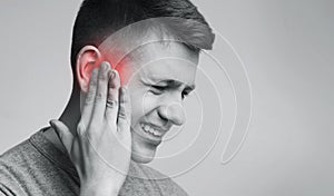 Portrait of man touching inflamed red ear photo