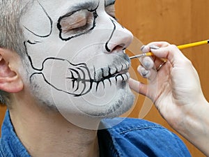 .portrait of man with traditional mexican halloween makeup, caballero celebrating day of the dead, face art, body art, photo