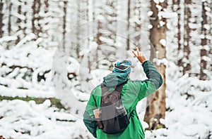 Portrait of man traveler in cap with backpack in winter forest