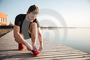 Portrait of a man tying shoelaces on sports shoe