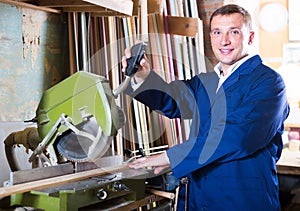 portrait of man in uniform working on electrical rotary saw indoors