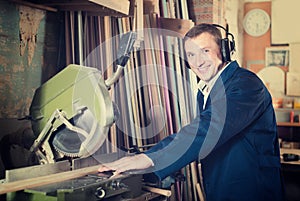 portrait of man in uniform working on electrical rotary saw indoors