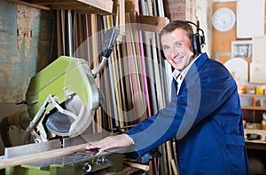 portrait of man in uniform working on electrical rotary saw indoors
