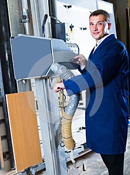 portrait of man in uniform working on large automatic saw machinery indoors