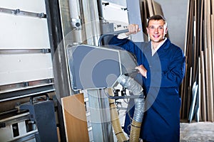 portrait of man in uniform working on large automatic saw machinery indoors