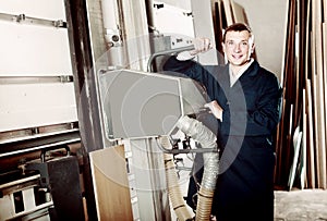 portrait of man in uniform working on large automatic saw machinery indoors