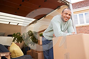 Portrait Of Man Unloading Furniture From Removal Truck Outside New Home On Moving Day