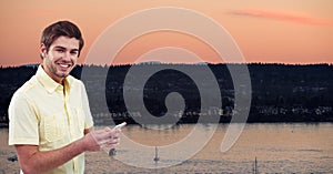 Portrait of man using mobile phone against lake