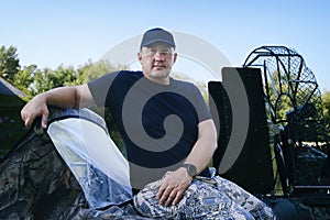 portrait of a man on vacation in nature, riding an airboat on the river in hunter's clothes