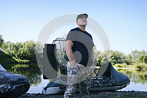 portrait of a man on vacation in nature, riding an airboat on the river in hunter's clothes