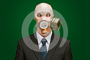 Portrait of a man wearing a dark business suit and a gas mask, isolated on green background