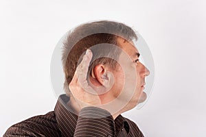 Portrait of a man wearing hearing aid and cupping his hand behind his ear.