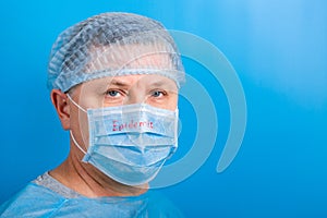 Portrait of man wearing medical uniform and protective mask with epidemic word at blue background. and health care