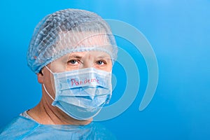 Portrait of man wearing medical uniform and protective mask with pandemic word at blue background. and health care