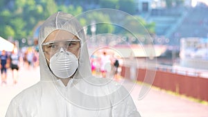 Portrait of man wearing respiratory mask and protective suit standing outdoors and looking around.