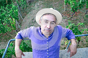 Portrait of man in straw hat sitting on bench on hill