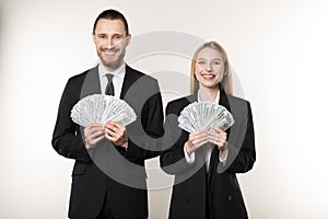 Portrait of man and woman in black suit holding fan of dollar money smiling and looking at camera