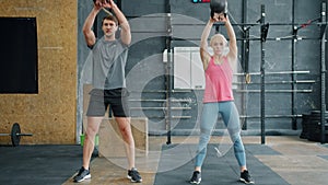 Portrait of man and woman exercising with kettlebells in modern crossfit gym