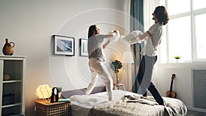 Portrait of man and woman having fun with pillow fight then kissing in bed