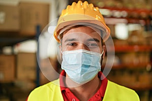 Portrait of man worker inside warehouse wearing safety mask for coronavirus prevention - Logistic and Industry concept - Focus on