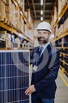 Portrait of manager holding a solar panel in a warehouse.