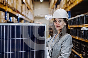 Portrait of manager holding a solar panel in a warehouse.