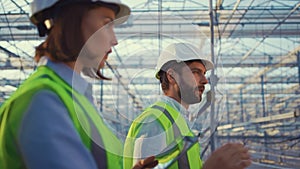 Portrait manufacture workers talking about production plan inspecting greenhouse