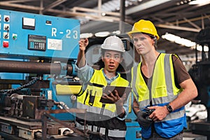 A portrait of a manufacturing worker in discussion with an industrial man and woman engineer holding a tablet in a factory. A