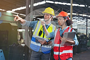 A portrait of a manufacturing worker in discussion with an industrial man and woman engineer holding a tablet in a factory. A