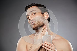 Portrait of masculine sexual man putting perfume aftershave on h photo