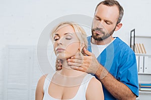 portrait of massage therapist massaging neck of young woman