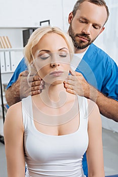 portrait of massage therapist massaging neck of young woman