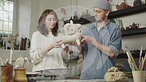 Portrait of master ceramists holding their products in their hands in workshop