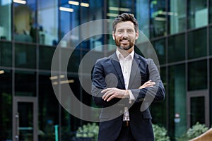 Portrait of mature adult businessman, senior boss with beard smiling and looking at camera, experienced and successful