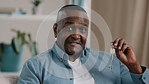 Portrait mature african american male happy homeowner showing keys to new apartment smiling looking at camera realtor