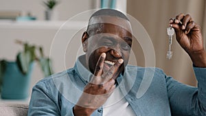 Portrait mature african american male happy homeowner showing keys to new apartment smiling looking at camera realtor