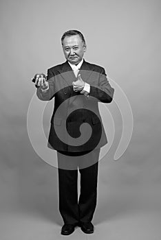 Portrait of mature Asian businessman against gray background