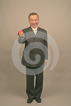 Portrait of mature Asian businessman with apple