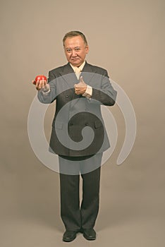 Portrait of mature Asian businessman with apple