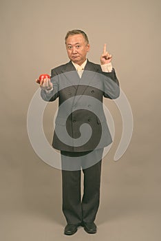 Portrait of mature Asian businessman with apple