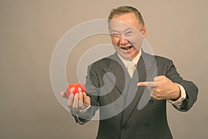 Portrait of mature Asian businessman with apple