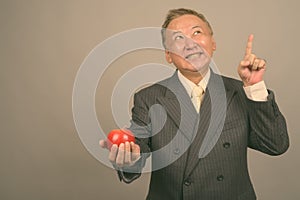 Portrait of mature Asian businessman with apple